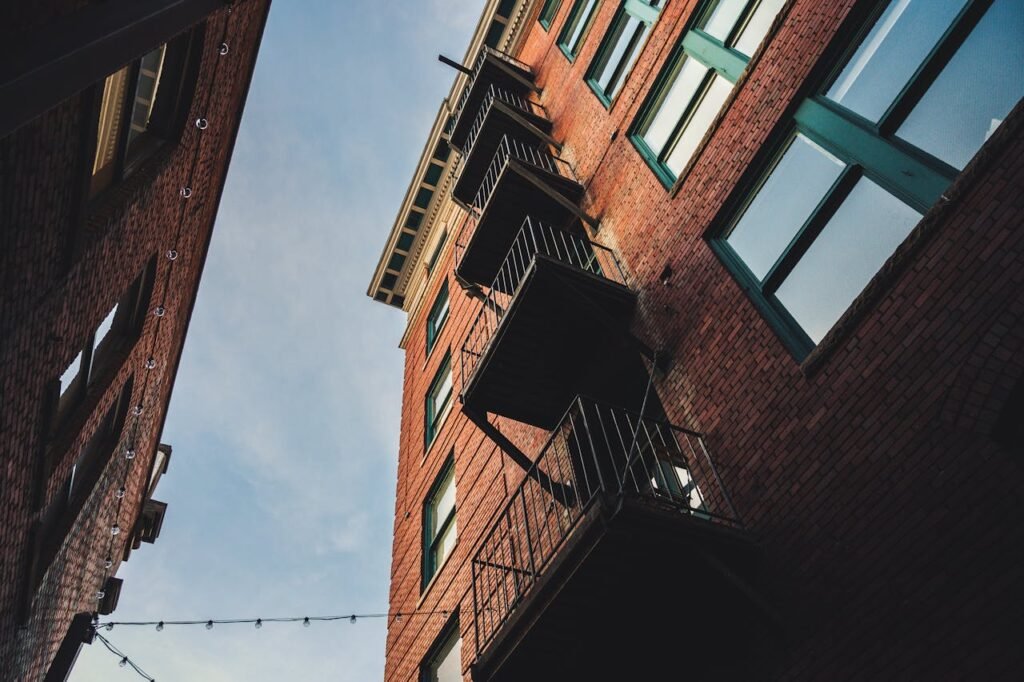 A striking low angle shot of red brick urban architecture and balconies under a clear sky.